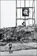 On the outskirts of Kabul, a boy waits beneath an image of the late Ahmed Shah Massoud.