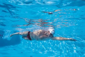 In the water, think long, think narrow. The keys to a more efficient freestyle stroke are to let yourself sink horizontally just below the waterline