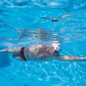 In the water, think long, think narrow. The keys to a more efficient freestyle stroke are to let yourself sink horizontally just below the waterline