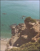 Kayakers paddle around a rocky outcropping near Sweetwater Beach.