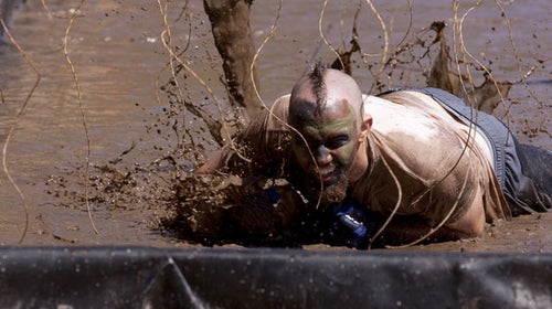A participant crawls under live wires during a Tough Mudder event.