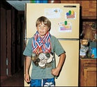 Lucky guy: Roger at home in Placerville, California, weighed down by 89 of his snowboarding medal