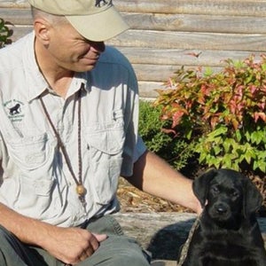 Mike Stewart with a young black Labrador Retriever.