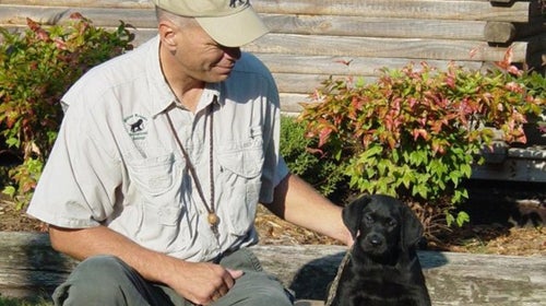 Mike Stewart with a young black Labrador Retriever.