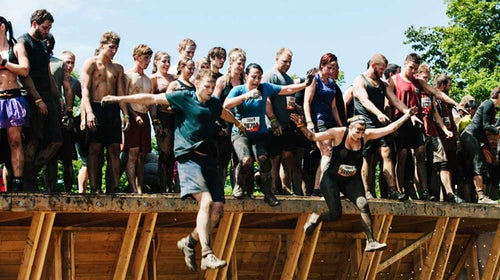 Participants leap off a platform in Tough Mudder's Walk the Plank obstacle.