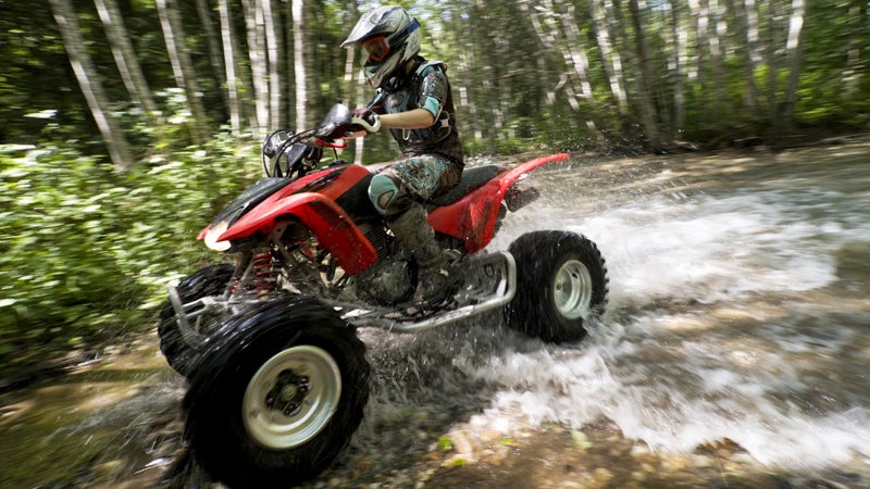 Female riding ATV through creek