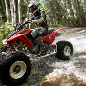 Female riding ATV through creek
