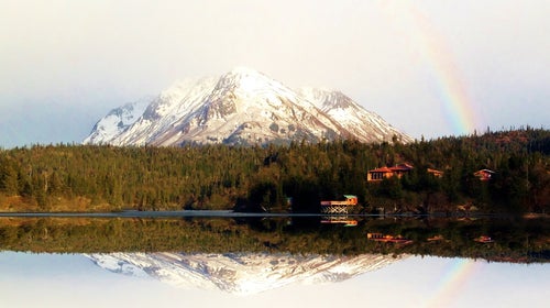 mountain range with a rainbow and calm lake