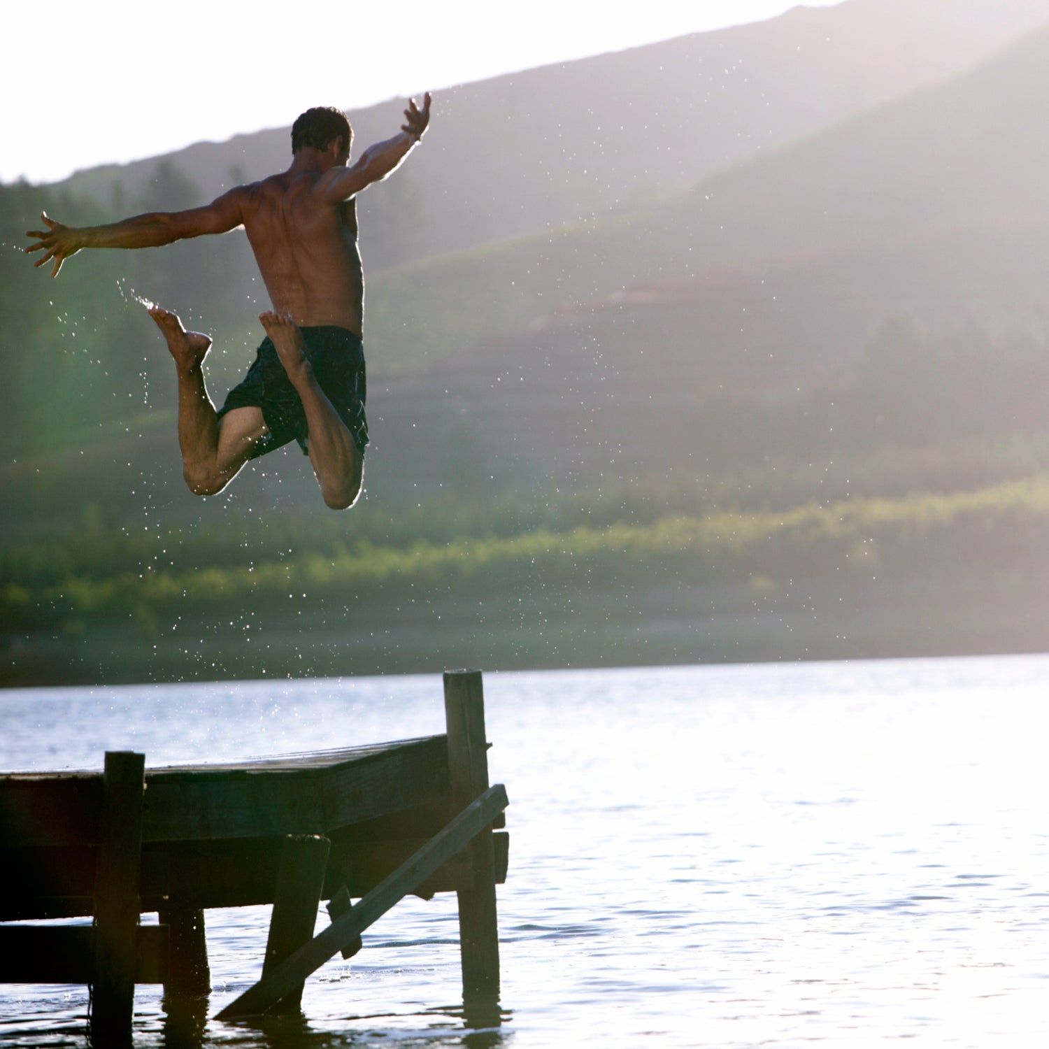 Мужчина через реку. Мужчина в прыжке. Мужчина прыгает в реку. Парень прыгает в озере.