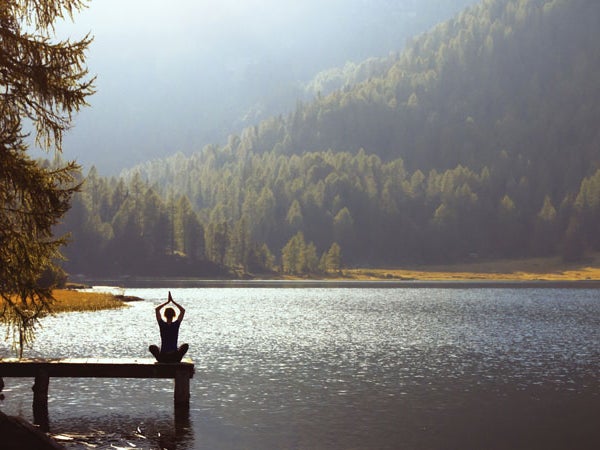 woman meditating on a lake with the best meditation apps