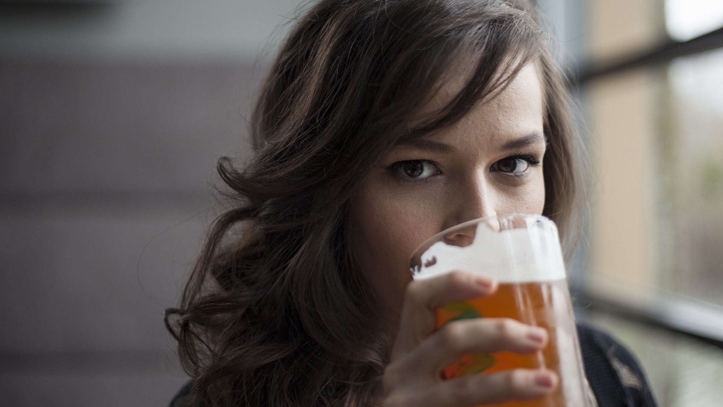 Young Woman Drinking a Pint Glass of Pale Ale