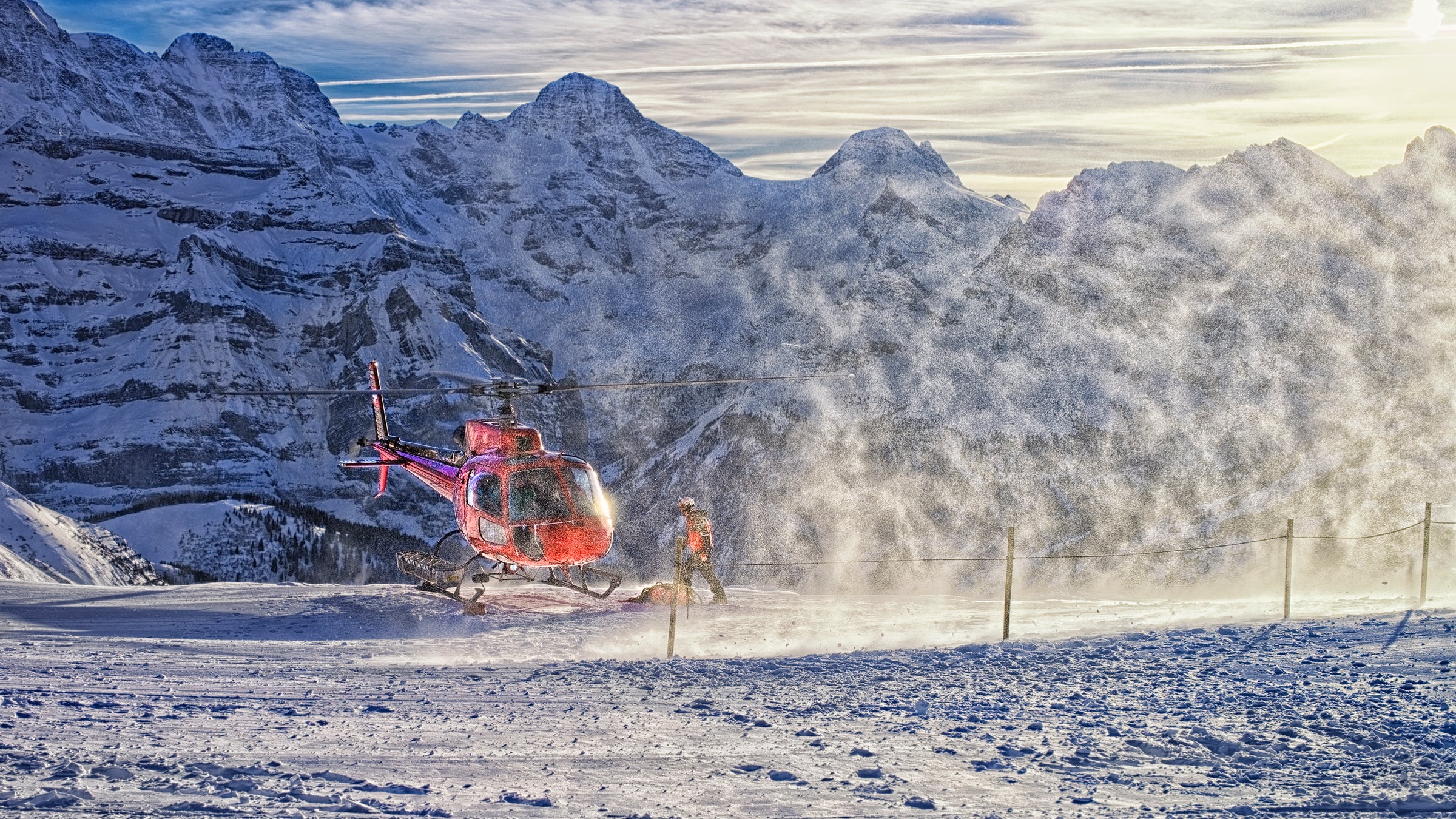 Switzerland alps mountain winter swiss helicopter aviation landing rock resort ski Maennlichen jungfrau peak highland holidays snow flakes flare sunlight slope sunshine red white blue activity serviceman vacation vessel vehicle flight