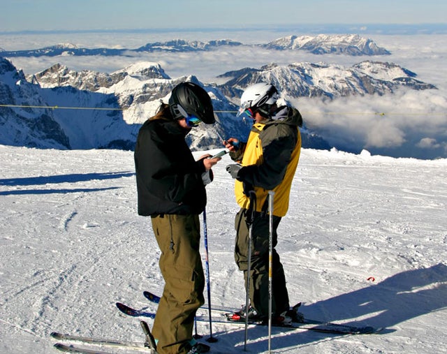 Two skiers calling from their cell phones on top of mount Titlis Switzerland