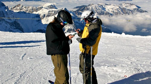 Two skiers calling from their cell phones on top of mount Titlis Switzerland