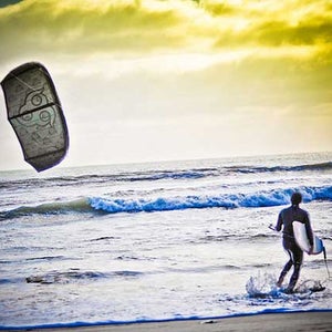 A kitesurfer heading out into the waves