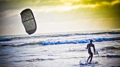A kitesurfer heading out into the waves