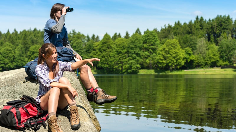 Teenage hikers birdwatching at lake