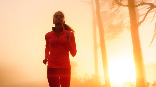 woman running through a forest at dusk