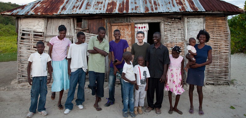 Ervenson (center, purple shirt) and his family pose with the author in front of their house in La Tortue.