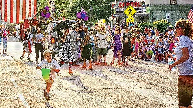 running Montpelier Mile July 4 footrace. in Montpelier Vermont joyful boy running towards mother spectators watching cast of Midsummer Night's Dream Shakespeare production by Lost Nation Theater American Flag State Street outside best towns ever