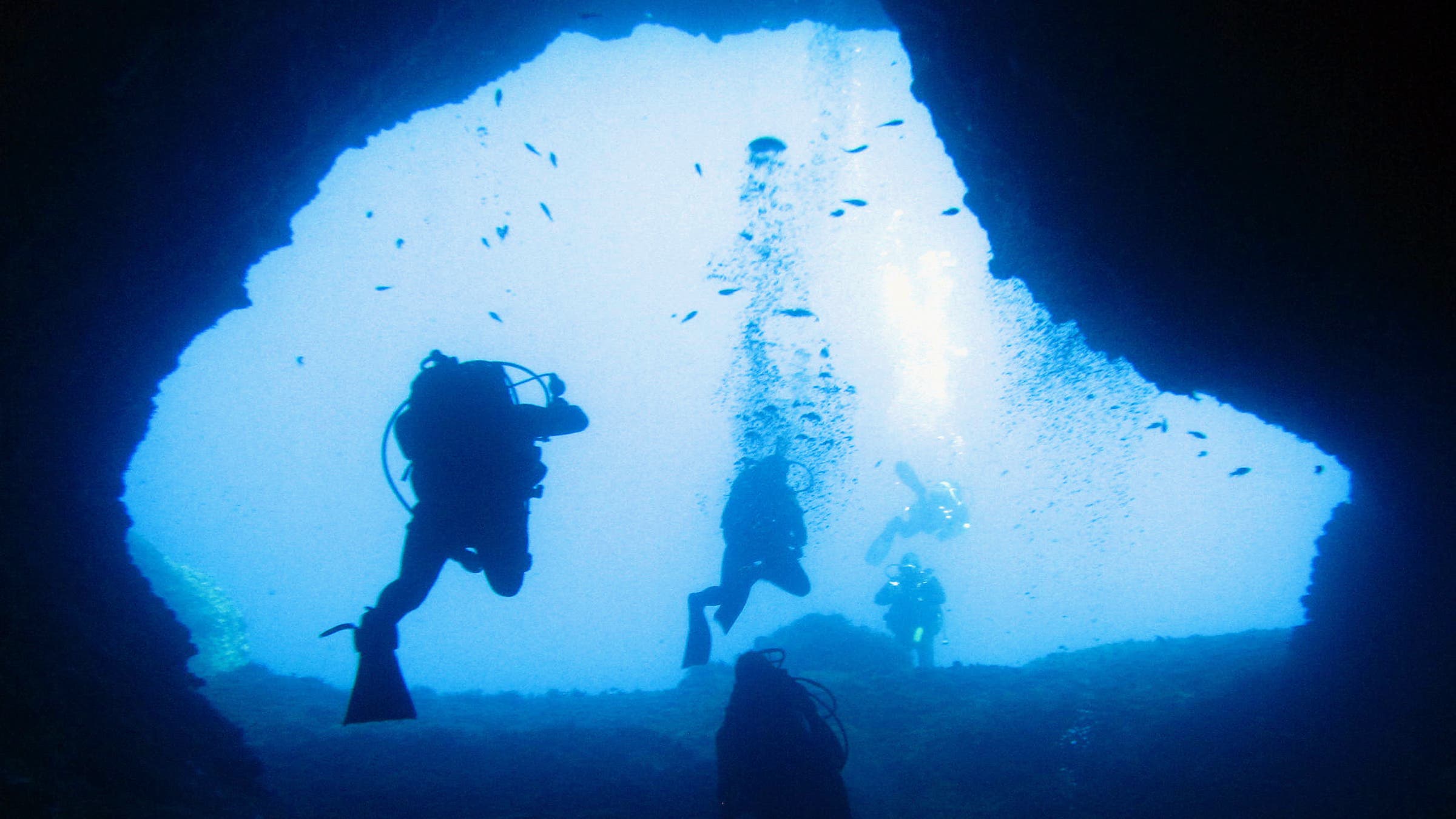 looking up underwater at people scuba diving in crete