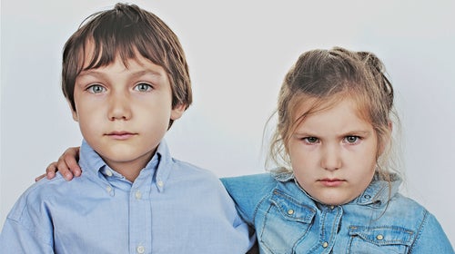 4-5 Years Anger Bonding Boy Brunette Hair Casual Clothing Caucasian Ethnicity Childhood Children  Only Friendship Front View Girl Hugging Indoors Innocence Leisure Lifestyles Looking At Camera Portrait Serious Sibling Simplicity Studio Shot Togetherness Two People Waist Up White Background